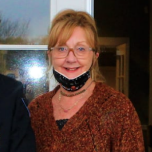 a woman wearing a neck gaiter and glasses standing next to a man