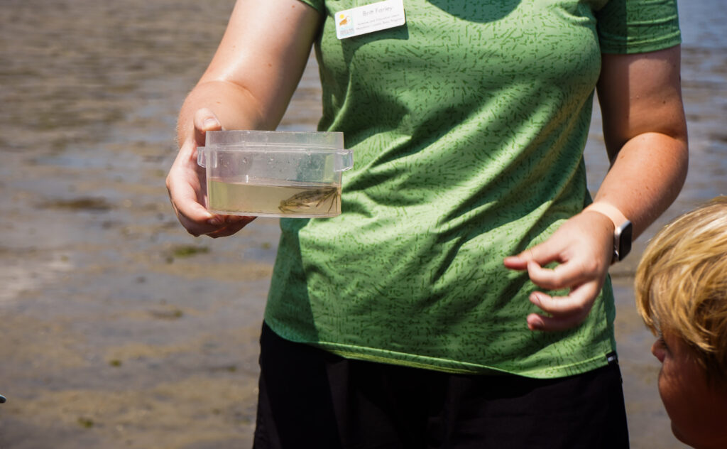 a woman holding a container with a small fish in it