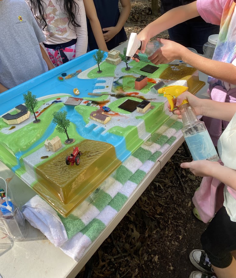 a group of children standing around a table with a cake on it