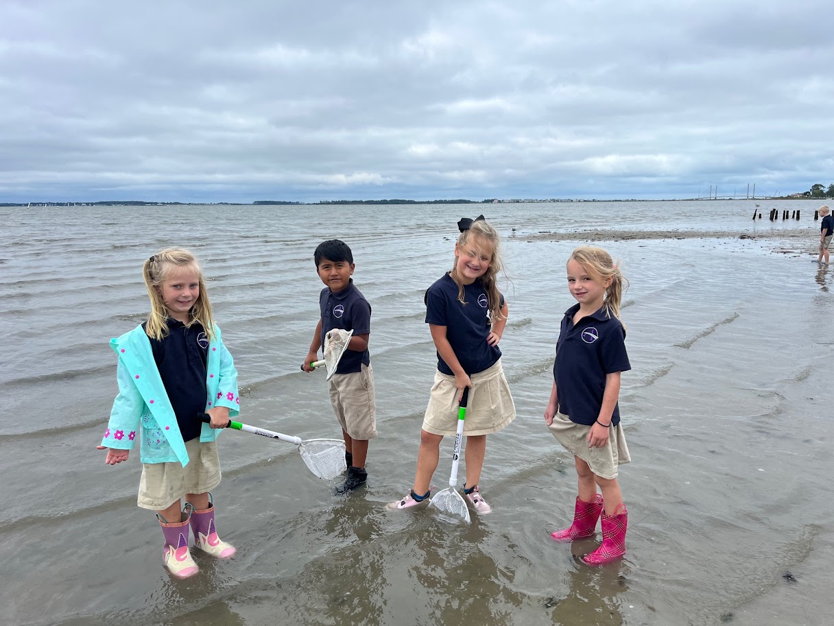 four children are standing in the shallow water