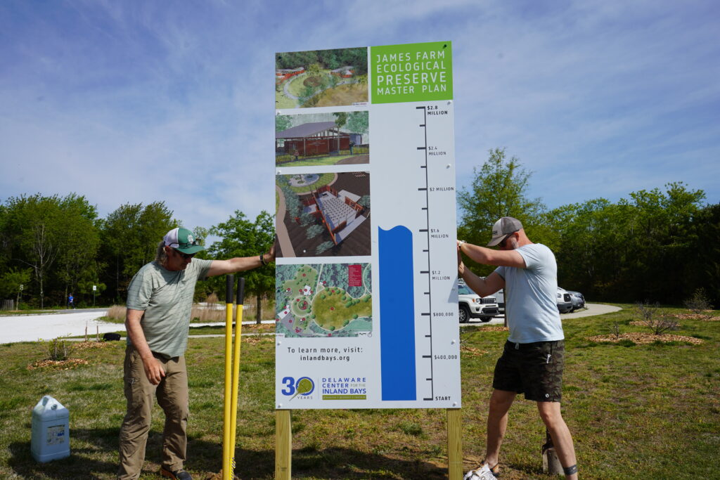 Two Center staff members install the progress sign for the James Farm Ecological Preserve Master Plan.